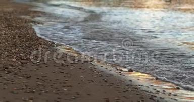 在沙滩上用许多小石头冲过的海浪特写